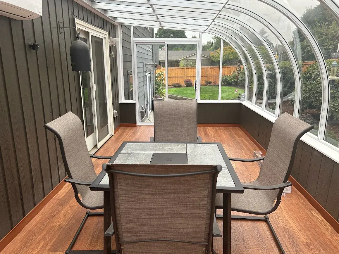 Bright sunroom sitting area with curved windows and patio furniture